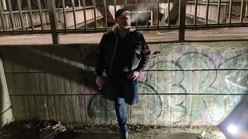 Dominus Andreas G. steht rauchend an Wand gelehnt