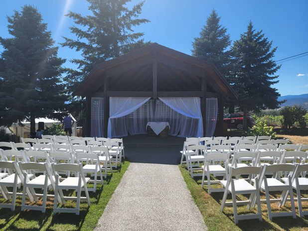Rustic pavilion wedding ceremony with white chairs and scenic mountain backdrop by Natural Touch Weddings.