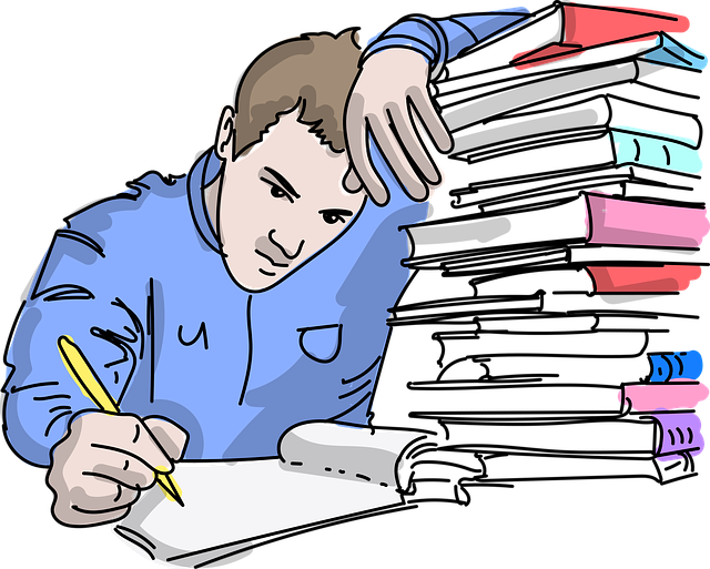 Stack of instructional materials; male student writing while in notebook while leaning on the stack of books.