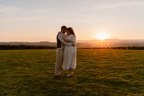 Bride and Groom holding each other during golden hour at Holsome Park, with rolling hills in the distance