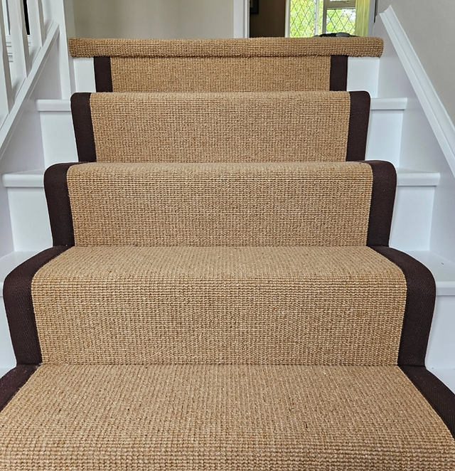 A gold coloured stair runner with black cotton binding tape on the edges