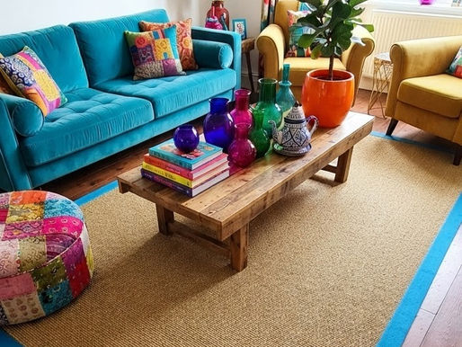 A vibrant living room showcases a sisal area rug with a striking blue tape border, complemented by colourful furniture and décor.