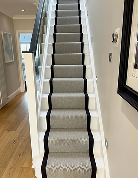 A grey stair runner with black basketweave cotton tape on the edges