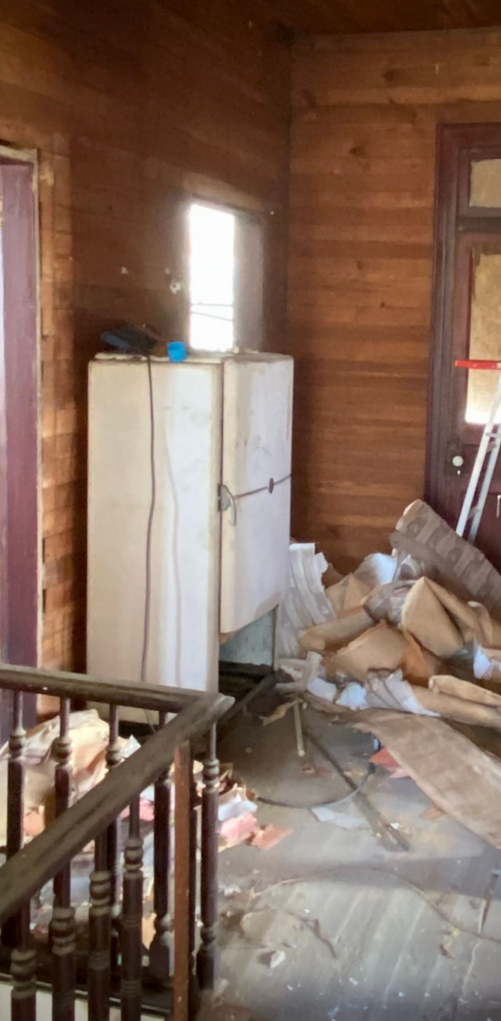 Old vintage refrigerator sitting in second-story hallway of 1898 Victorian farmhouse with natural light and original floors