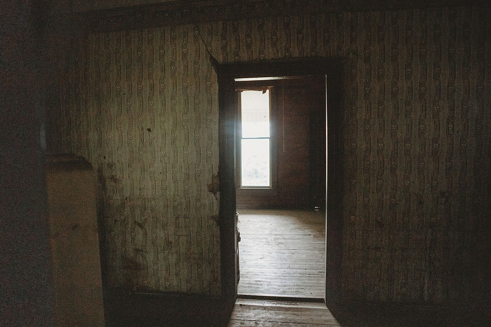 Dark second story hallway in 1898 Victorian farmhouse with natural light coming through doorway and original worn walls