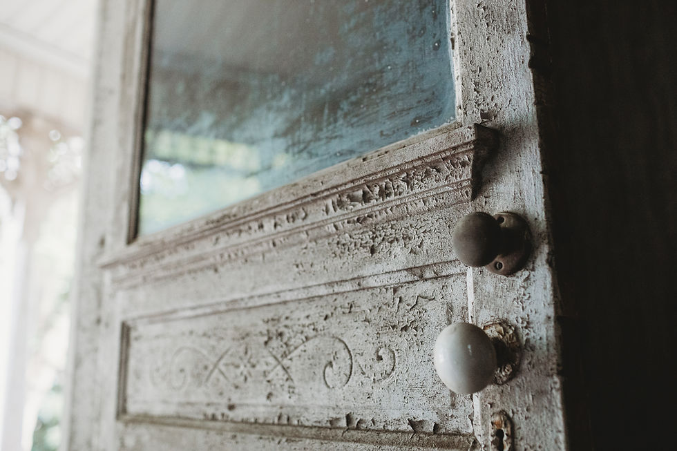 Close-up of Eastlake-style Victorian door with ornate carved detail and aged painted surface in historic farmhouse