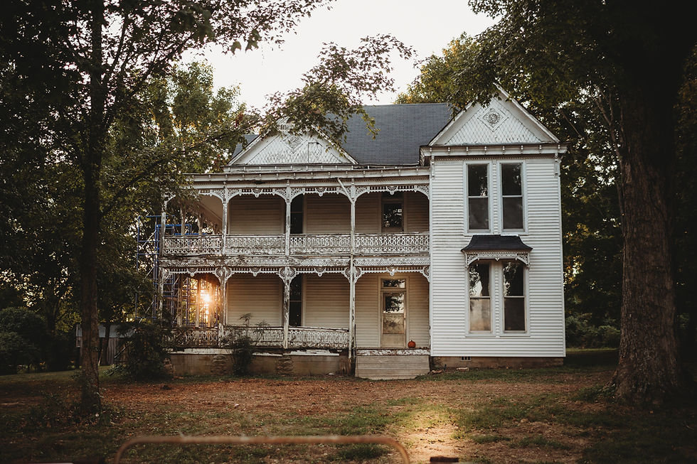 Front view of 1898 Victorian Farmhouse in Tennessee with double wrap-around porch, ornate trim, and two-story structure framed by trees.