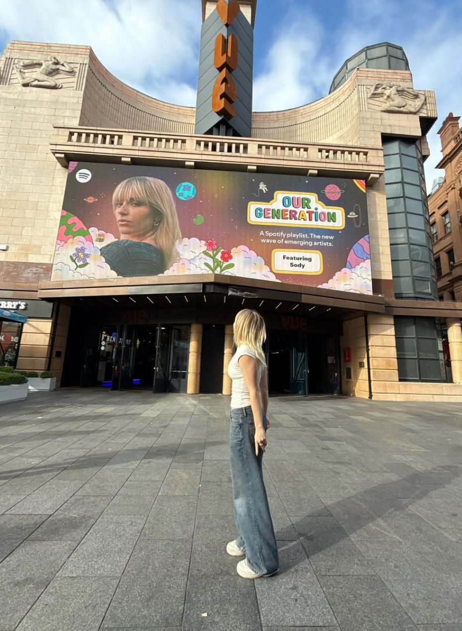 Photo of Sody outside Leicester Square with a billboard of her on it. Photo via Sody on Instagram (@sody)