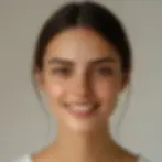A person with long dark hair smiles at the camera against a neutral background, radiating confidence and showcasing the subtle effects of botox injections.