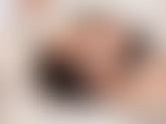 Person receiving scalp injection from gloved professional. Lying on white sheet, eyes closed. Calm setting, close-up view.