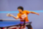 Table tennis player Sambit Kanjilal bending low in a focused stance preparing to push a forehand shot during a match.