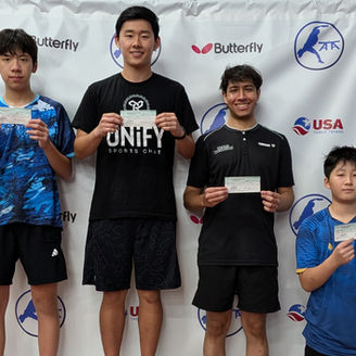 Four table tennis players holding award certificates on a podium at the ATTC tournament.
