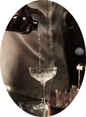 A dark bottle pouring a hemp infused non-alcoholic CBD spirit alternative into a crystal coupe glass with an elegant, dark setting for alcohol free cocktails or mocktails.