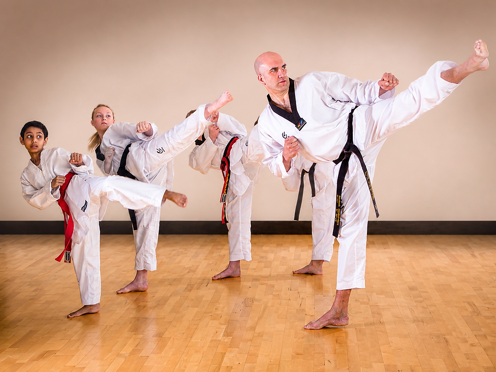 Eye-level view of a taekwondo student practicing a high kick in a bright training hall
