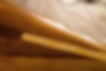 Detailaufnahme der glänzenden Epoxidharzoberfläche eines frisch laminierten Leistenkanus. In die passgenaue Beplankung aus roten Red-Cedar Holzleisten ist ein heller Eschenstreifen eingearbeitet