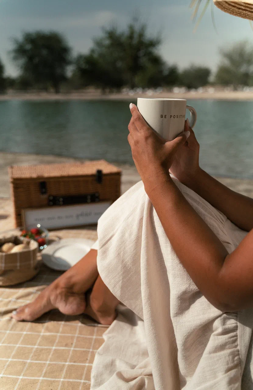 A woman enjoying her morning coffee at a Dubai luxury picnic by PicnicTimes, embracing simplicity and relaxation.