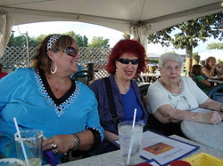Barbara Romain seated at an outdoor table with Mara Wave, and her Mom