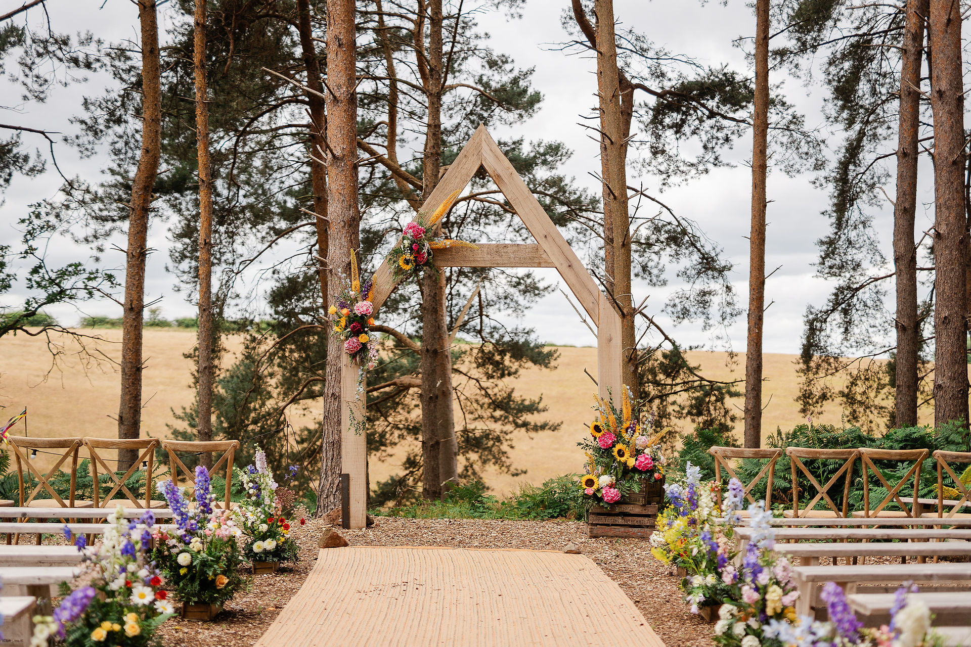 outdoor woodland ceremony setting with bright colourful flowers wedding photography bridal barn venue claverley