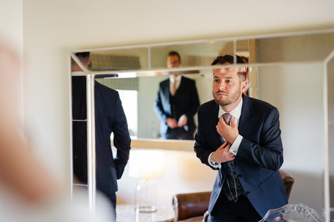 Photo of groom adjusting his tie in the mirror at The Ashes Barns wedding venue Stoke-on-Trent