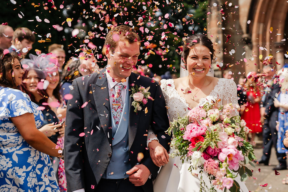 Bride and groom covered in flower petal confetti during a joyful Staffordshire wedding exit.