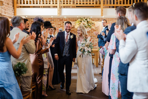 Photo of bride and groom happy and smiling as they walk back down the aisle after their ceremony at The Ashes Barns wedding venue Stoke-on-Trent