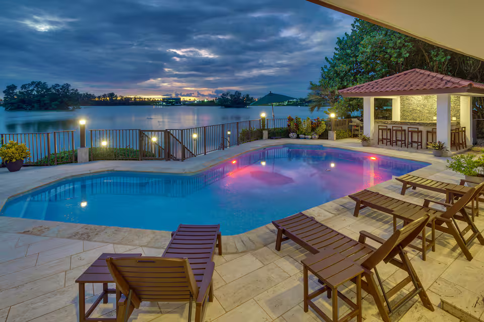 Luxury lakefront Airbnb home in Miami with heated pool, outdoor lounge area, dock, gym, sauna, and spacious interiors for up to 12 guests.