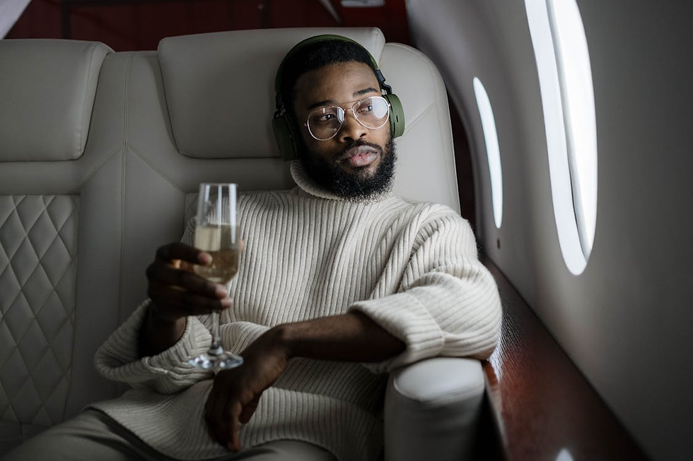 Man relaxing with champagne on a private jet, wearing headphones and glasses, symbolizing luxury lifestyle, wealth mindset, and financial freedom.