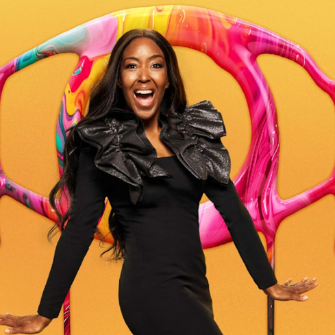 Angellica Bell wearing a ruffled black dress poses joyfully in front of a colorful, abstract backdrop, hinting at her rumored Strictly Come Dancing 2025 appearance.