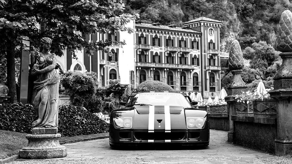 Black-and-white image of a classic luxury sports car with racing stripes parked on a stone driveway in front of an ornate estate, symbolizing long-term vision, legacy, patience, and the rewards created by years of disciplined work.