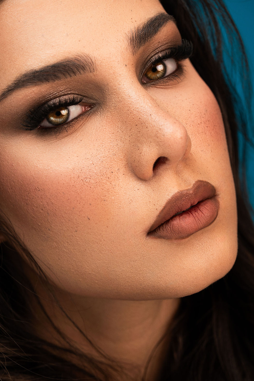Close-up beauty portrait of a woman wearing rich chocolate brown smoky eyeshadow, dramatic lashes, softly defined brows, and matte cocoa-brown lipstick. Her warm complexion, natural freckles, and softly sculpted cheeks complement the espresso-inspired makeup look, highlighting the chocolate brown beauty trend for fall 2026.
