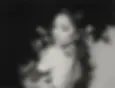 Black-and-white promotional image of Ariana Grande looking over her shoulder with soft lighting and a blurred background.