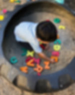 child paying in the sandbox in the backyard at Orkidz Preschool