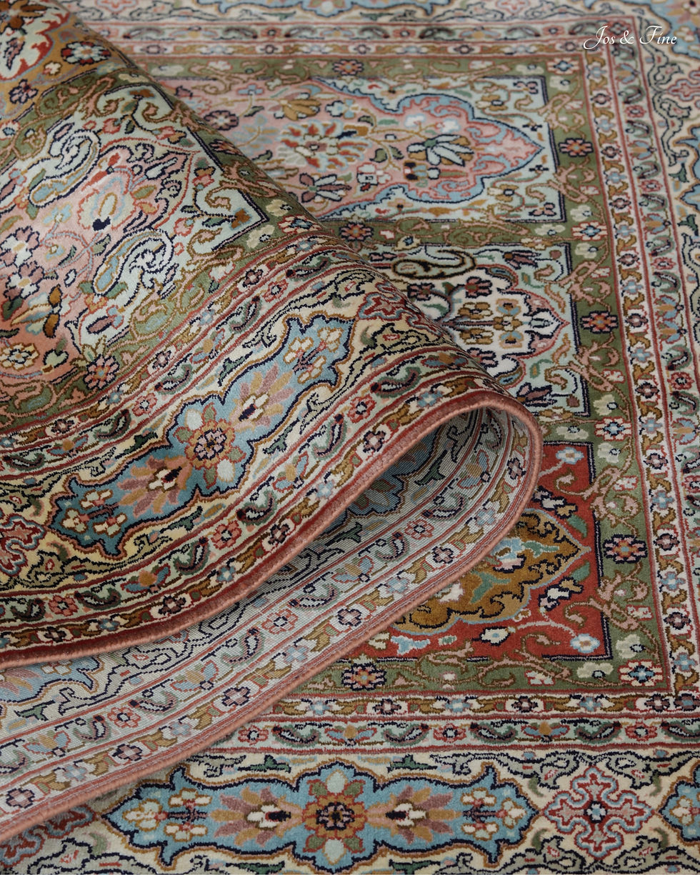 Folded detail showcasing intricate borders and pastel pure silk pile of a Kashmiri carpet.