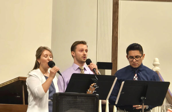 a mother and an adult son sing a duet in church service together