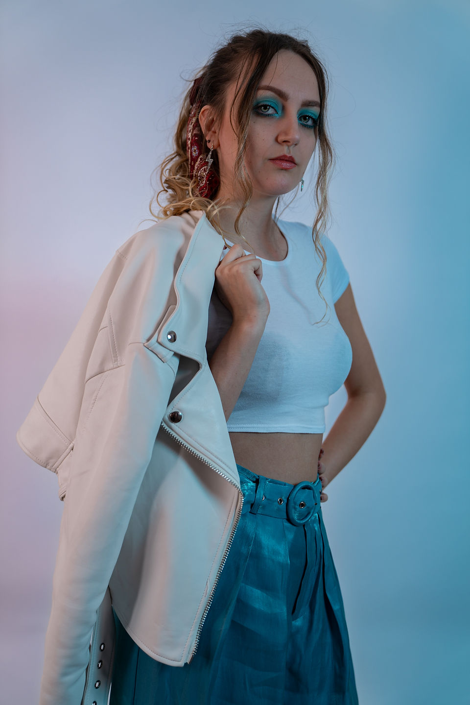 Woman Holding White Leather Jacket Over Her Shoulder In Blue and Red Studio Lights. Inspired by David Bowie, Legacy.
