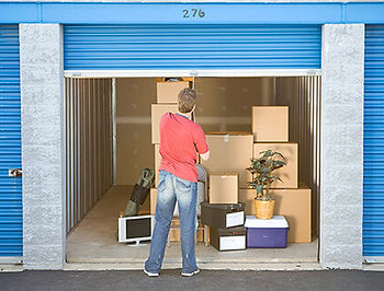 person lowering the shutter of a storage unit that contains household items