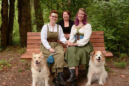 Kiki Stephens behind two women who are seated on a bench with their dogs_proportional_resi