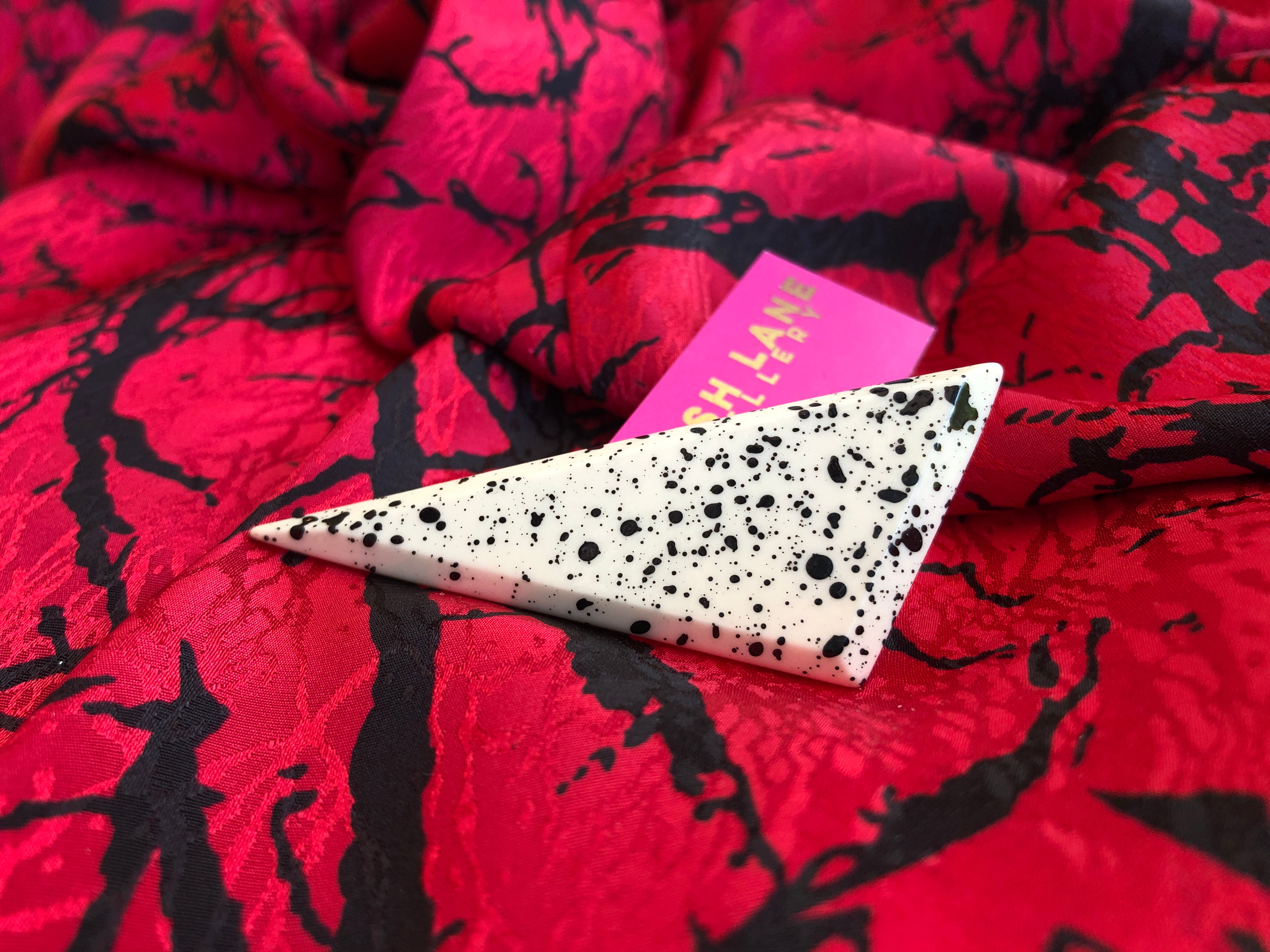 Pin's triangulaire moucheté blanc et noir