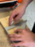 Hands using a speed square and pencil to mark wood