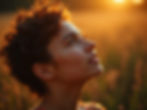A person with curly hair gazes up in a sunlit field, with warm golden tones creating an atmosphere of serenity and contemplation.