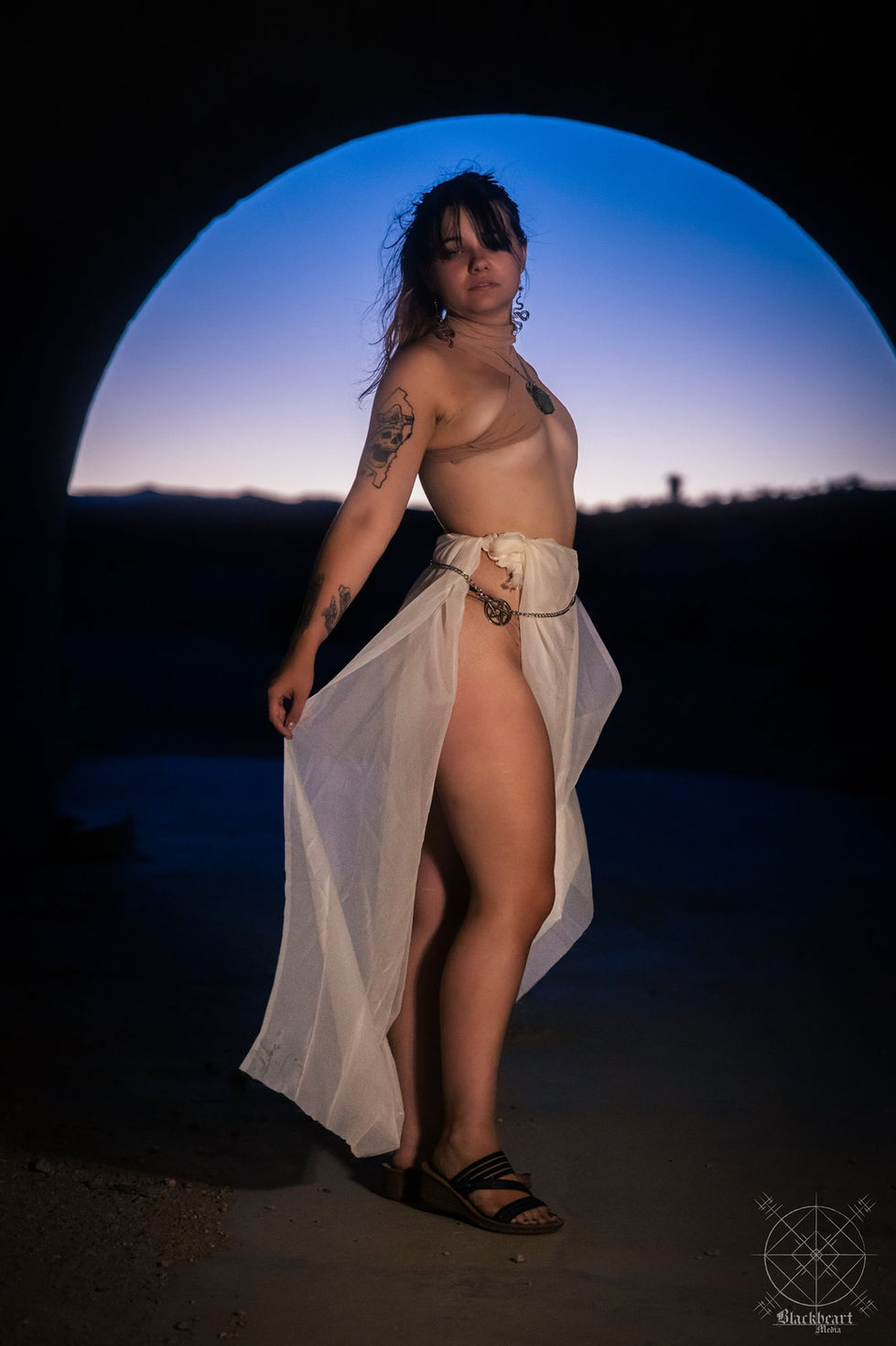 Shayla posing in a sheer white skirt beneath a tunnel arch at blue hour