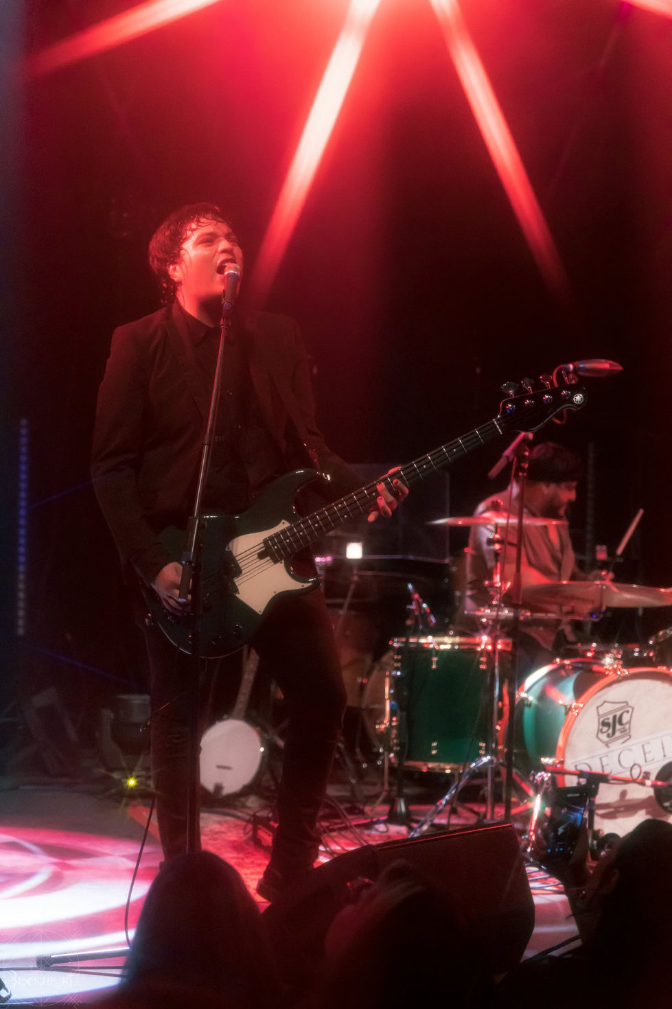 Bassist under red beams of light at center stage