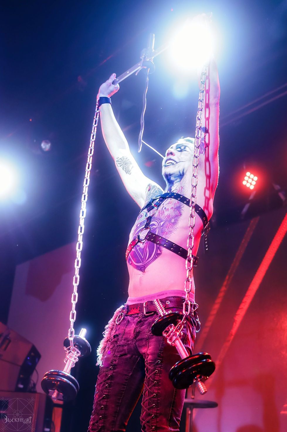 Auzzy Blood lifting chained weights overhead in a blue spotlight