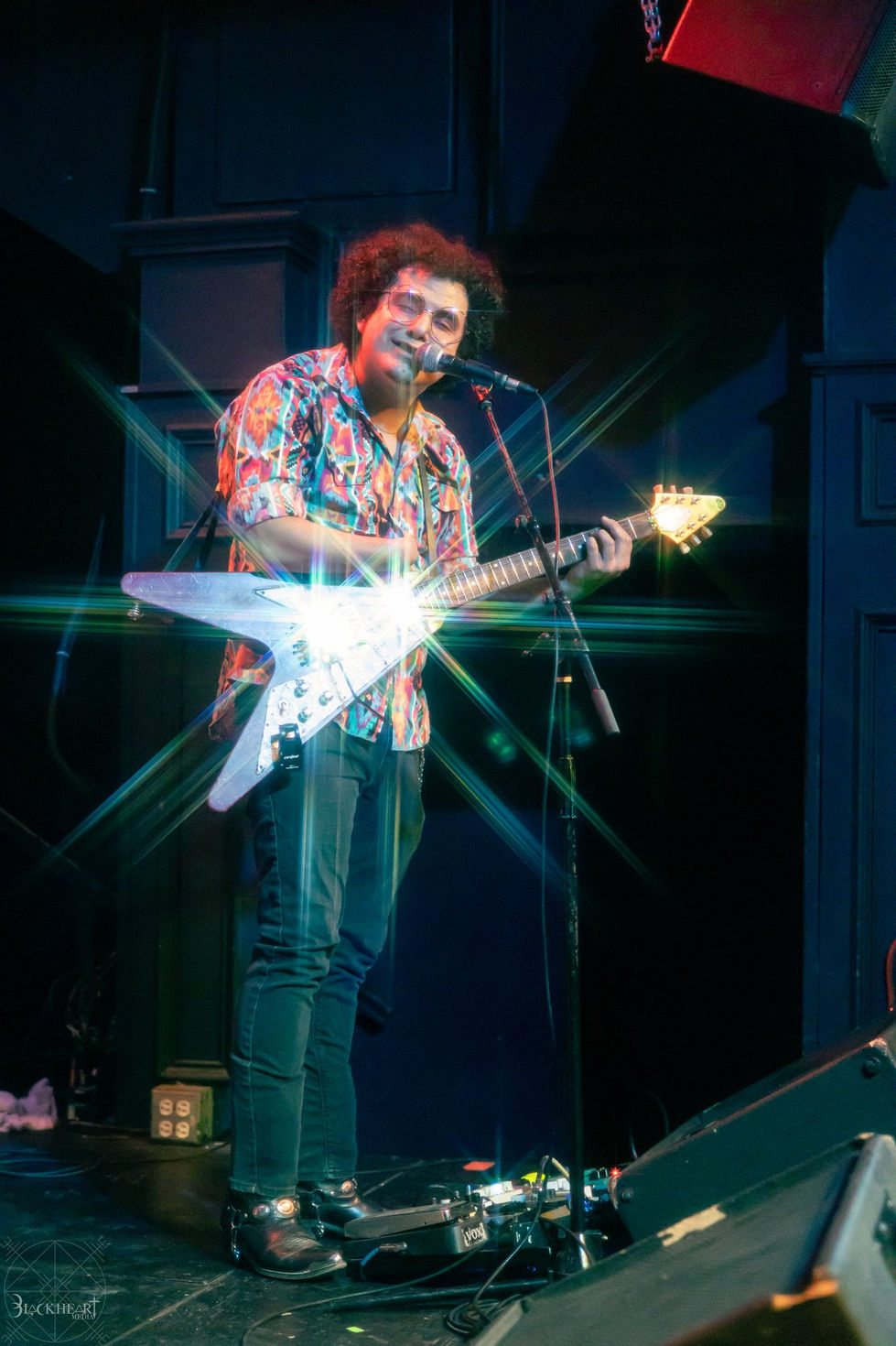 Guitarist with a white flying V under a starburst
