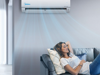 Lady relaxing under a Midea wall-mounted air conditioning unit cooling a living room