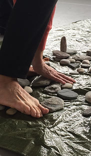 Two feet and one hand standing on pebbles