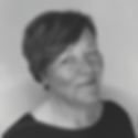Woman with short hair smiles softly against a plain background. Black and white photo. Mood is calm and pleasant.