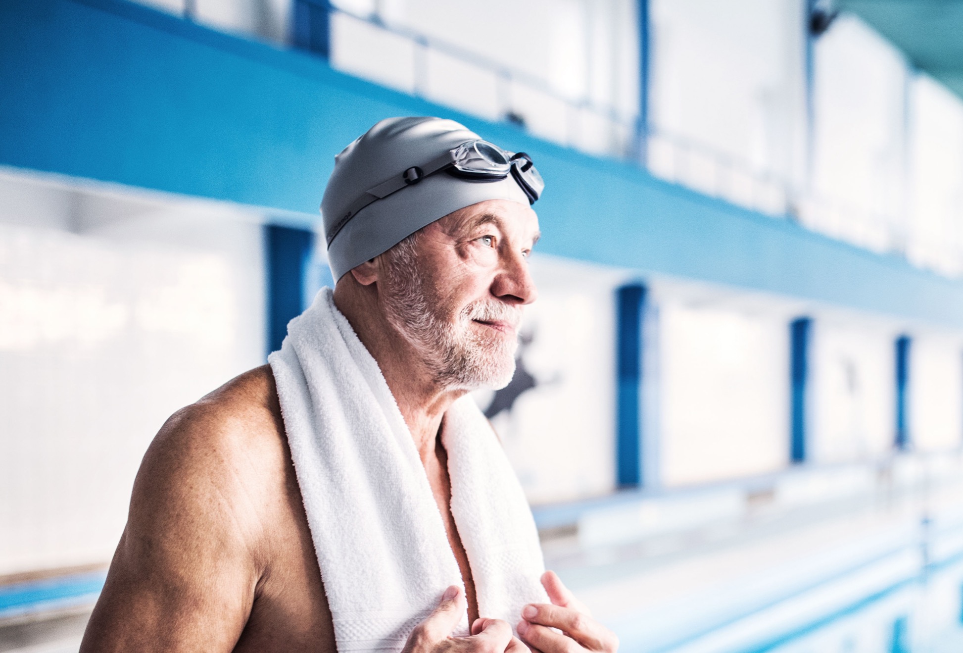 Ein älterer Herr, der in Badekleidung und Taucherbrille im Schwimmbad steht.
