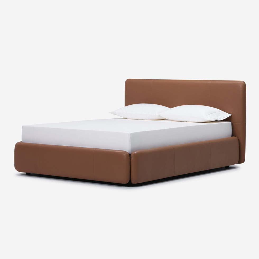 Brown leather platform bed with white linens