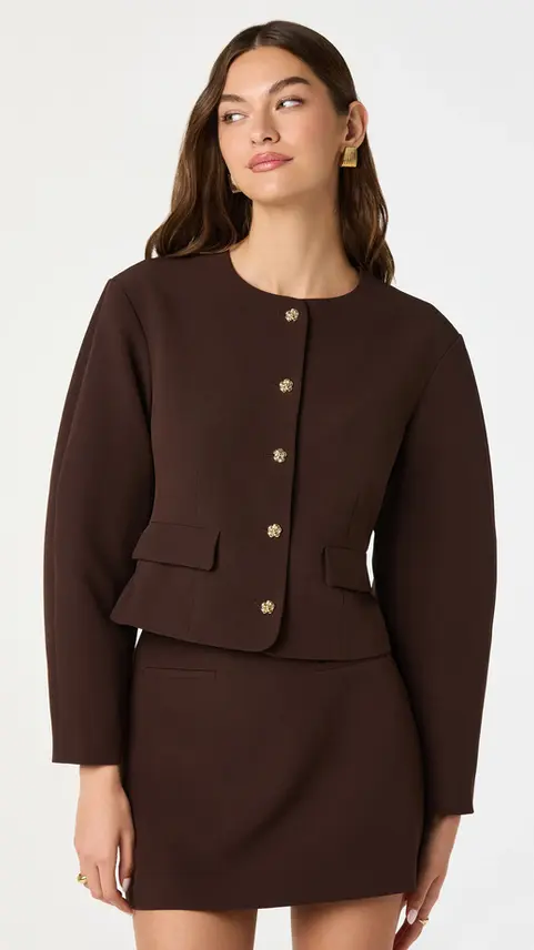 Woman wearing a brown collarless tailored blazer with gold buttons